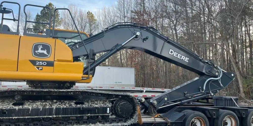 A John Deere 250 excavator loaded and chained down on a lowboy trailer