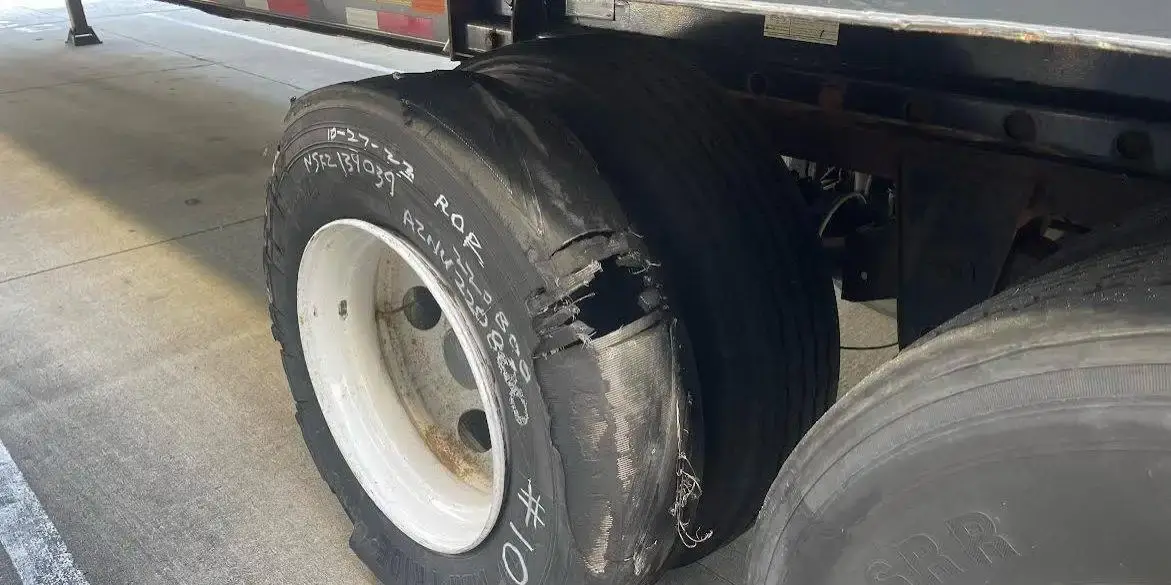 A shredded trailer tyre still on the rim, tread stripped away to the casing