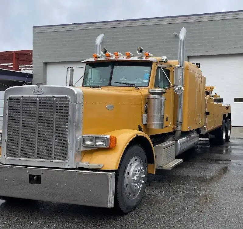 Tri City's yellow Peterbilt wrecker parked outside the Petersburg shop on a wet morning