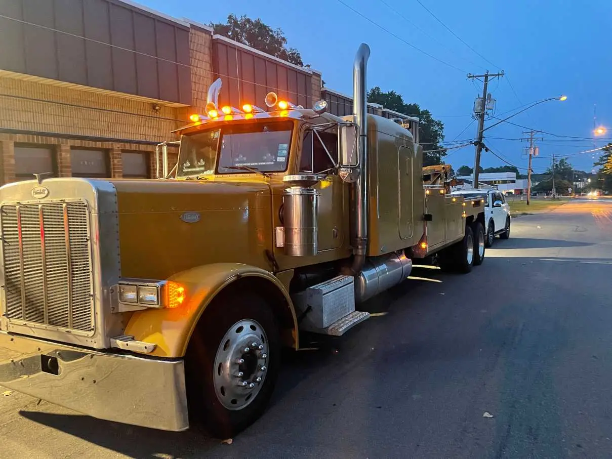 Tri City's wrecker towing a vehicle on a residential street at dusk